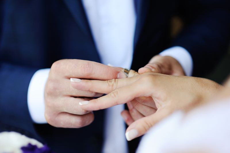 man putting wedding ring on wife