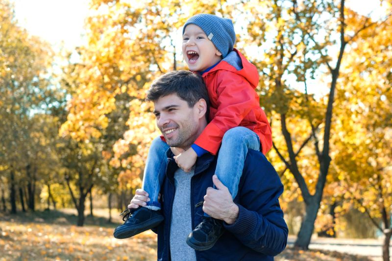 Father and toddler walking outside during the fall